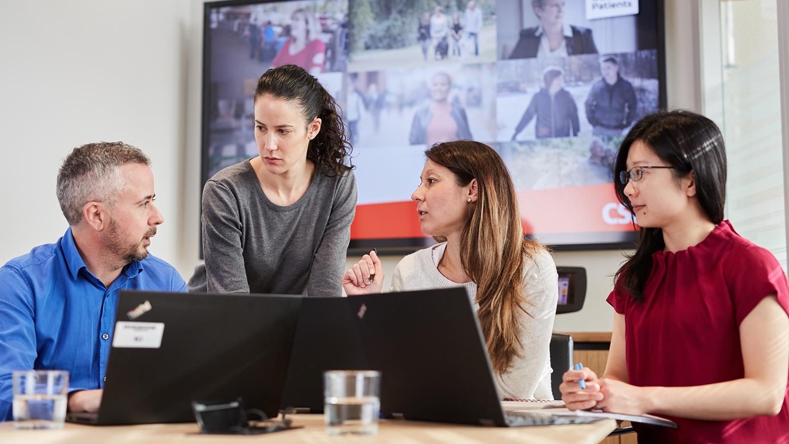 Photo of four employees having a discussion at an office table